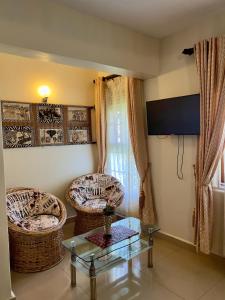 恩德培Sunset Hotel Entebbe的客厅配有两把椅子和一张玻璃桌