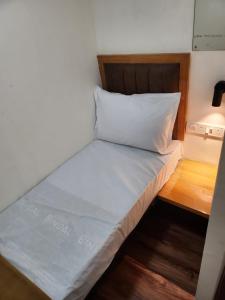 孟买Galaxy Cabin Stay And Dormitory的一张位于小房间的床,配有白色枕头