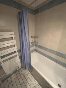勒图凯-巴黎普拉日Atlante15的浴室设有白色浴缸和蓝色的淋浴帘