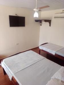 大坎普Pousada Estância Mineira的客房设有两张床和一台平面电视。