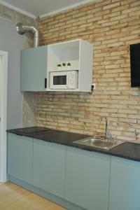 瓦伦西亚La Casa Verde - Ruzafa的厨房配有白色橱柜和砖墙上的微波炉