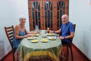 MonaragalaKande Gedara Resort (කන්දෙ ගෙදර)的坐在餐桌旁吃食物的男人和女人