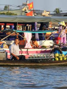 芹苴MEKONG DANIEL HOMESTAY CAN THO的坐在船边的人