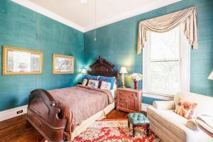 GonzalesBelle Oaks Inn的卧室拥有蓝色的墙壁,配有一张床和一张沙发