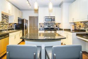 亚特兰大Landing - Modern Apartment with Amazing Amenities (ID3752)的一个带白色橱柜的厨房和一个带椅子的岛屿