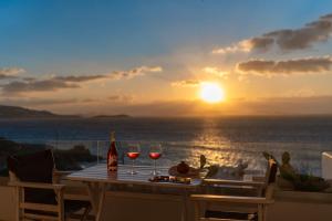 图罗斯With-inn Mykonos Suites的一张桌子,放上两杯葡萄酒,欣赏日落美景