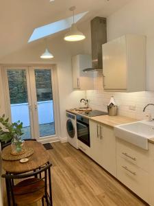 LaxeyThe Cottage, Bridge House的厨房配有白色橱柜、桌子和水槽。