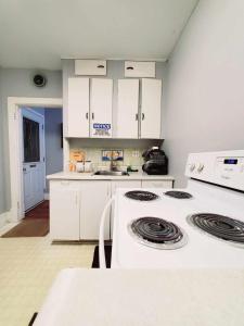 温尼伯Merj's Guest House in Wolesly的厨房配有白色橱柜和炉灶。