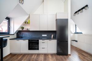 维尔纽斯Cozy Central Attic SELF Check In的厨房配有白色橱柜和黑色冰箱。