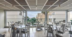 加藤-达拉特索Althea Village - Family Hotel的餐厅设有桌椅和大窗户。