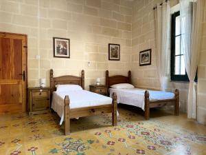 维多利亚Tal-Kaptan的一间卧室设有两张床和窗户。
