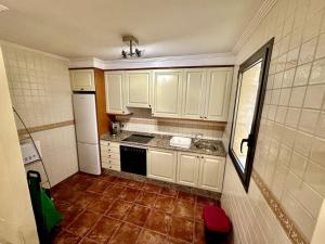 厄尔梅达诺Sol & Mar的厨房配有白色橱柜和瓷砖地板。