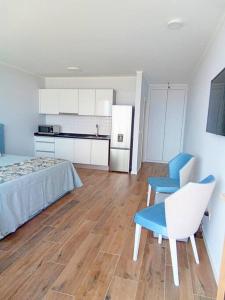 圣港Praia Encantada的一间卧室配有一张床和一把椅子,一间厨房