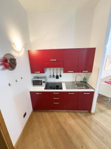 皮拉Monolocale sulle piste da sci的一间带红色橱柜和水槽的厨房