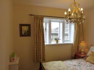 Slaithwaite伍登恩德度假屋的一间卧室设有窗户、一张床和一个吊灯。