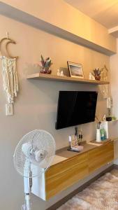 马尼拉Smdc Breeze Residences的客房设有一张桌子、一台电视和一个风扇。
