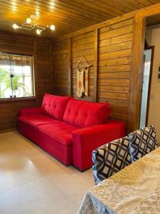 ItapemirimMillicent Residence - Chalet Milly e Chalet Iris - Itaoca Praia - ES的配有木墙的客房内的红色沙发