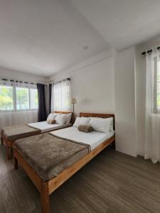 ManiwayaIslas Moriones Beach Resort的卧室设有两张床,拥有白色的墙壁和窗户。