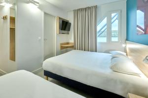 纳博讷Kyriad Direct Narbonne Sud的酒店客房设有两张床和窗户。