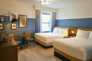 旧金山Hotel Julian的酒店客房带两张床和一张桌子以及椅子。
