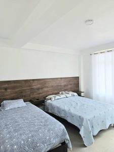 塔克纳Casa de Playa Luxury Laguna Azul Tacna的一间卧室设有两张床和窗户。