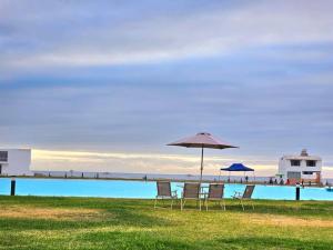 塔克纳Casa de Playa Luxury Laguna Azul Tacna的一组椅子和一把遮阳伞,位于游泳池旁