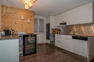 阿德尔博登Am Strubelweg的厨房配有白色橱柜和木墙