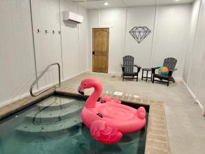 鸽子谷SmokiesBoutiqueCabins would love to host you at our NEW cabin! 3 King Suites, Indoor Pool, Game Room, Lounge with 75" TV! Close to Dollywood and the Parkway!的游泳池,室内有粉红色的天鹅