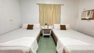 波尔多·格尼拉Manalo's Lodge and Restaurant的配有桌子和窗户的客房内的两张床