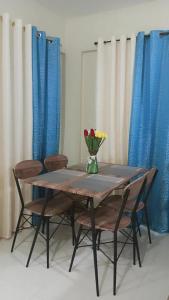 帕加迪安Pagadian Staycation in Camella 1的桌子上摆放着椅子,花瓶上放着花