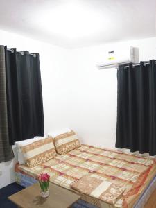 帕加迪安Pagadian Staycation in Camella 2的一张位于带黑色窗帘和桌子的房间的床铺