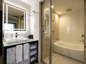 周南市Green Rich Hotel Tokuyama Ekimae的浴室配有水槽、淋浴和浴缸。
