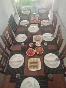 锡吉里亚AMRON RESORT SIGIRIYA的长木桌,盘子和碗