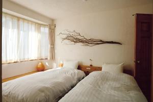 函馆SMALL TOWN HOTEL Hakodate的墙上有树枝的房间里设有两张床
