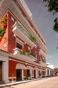圣玛尔塔Basilica Hotel的一座红色和白色的建筑,阳台上种有鲜花