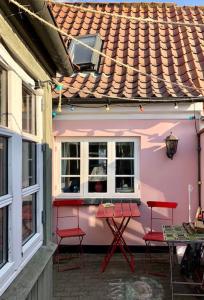 马斯塔尔Skønt fiskerhus. Tæt på by, havn og havet的粉红色的房子,配有红色的椅子和桌子