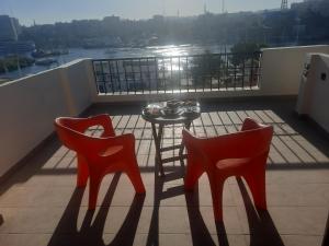 阿斯旺FADL Kato的阳台上配有两张红色椅子和一张桌子