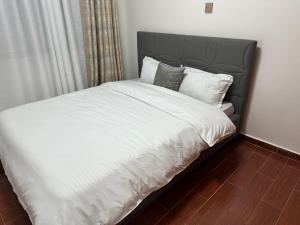 内罗毕Home Croft Nairobi的卧室内的一张带白色床单和枕头的床