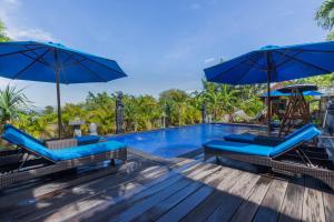 蓝梦岛Tatak Bunut Private Villa的度假村的游泳池,配有蓝色的椅子和遮阳伞