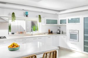 埃拉特By Eezy- דירה משפחתית מפנקת 3 חדרי שינה - Hanechoshet的白色的厨房,在柜台上放一碗水果