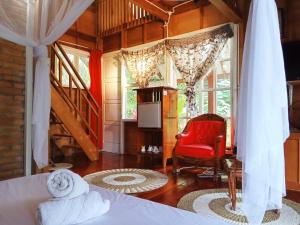 巴东Air Manis Hillside Villa Cafe & Resto的一间卧室配有一张床和一张红色椅子