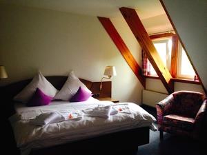 格尔利茨Dein Gutshof Hotel & Ferienwohnungen的一间卧室配有一张带紫色枕头的床和一把椅子