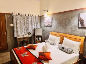 雅拉Yala Leopard Lodge的一间卧室配有白色床单以及橙色和白色枕头。