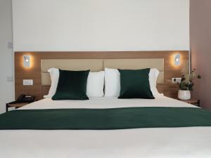 罗马Massimi City Garden的一间卧室配有一张带绿色和白色枕头的大床