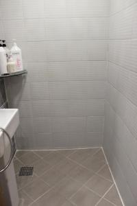 首尔Hostel JL in Chung-jeong的带淋浴的浴室和白色瓷砖墙壁