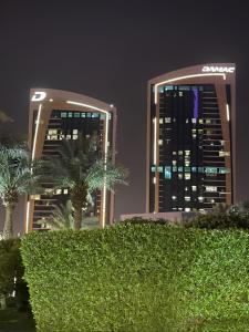 利雅德برج داماك الرياض DAMAC Towers Riyadh的两座高楼,前方有棕榈树