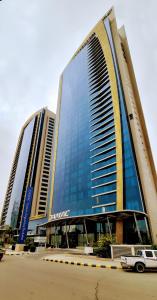利雅德برج داماك الرياض DAMAC Towers Riyadh的两座高楼,前面有一辆汽车