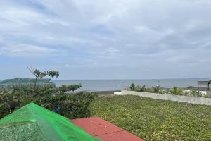 利安Lover's Point Beach Front Resort的海滩附近的草地上摆放着一把绿伞
