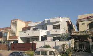 伊斯兰堡Morbex Guest House Islamabad的一座白色的建筑,前面有汽车停放