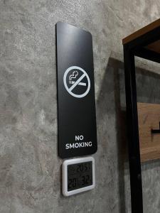 彼得罗巴甫洛夫斯克DEMAL HOTEL的墙上的时钟旁边有一个禁止吸烟的标志